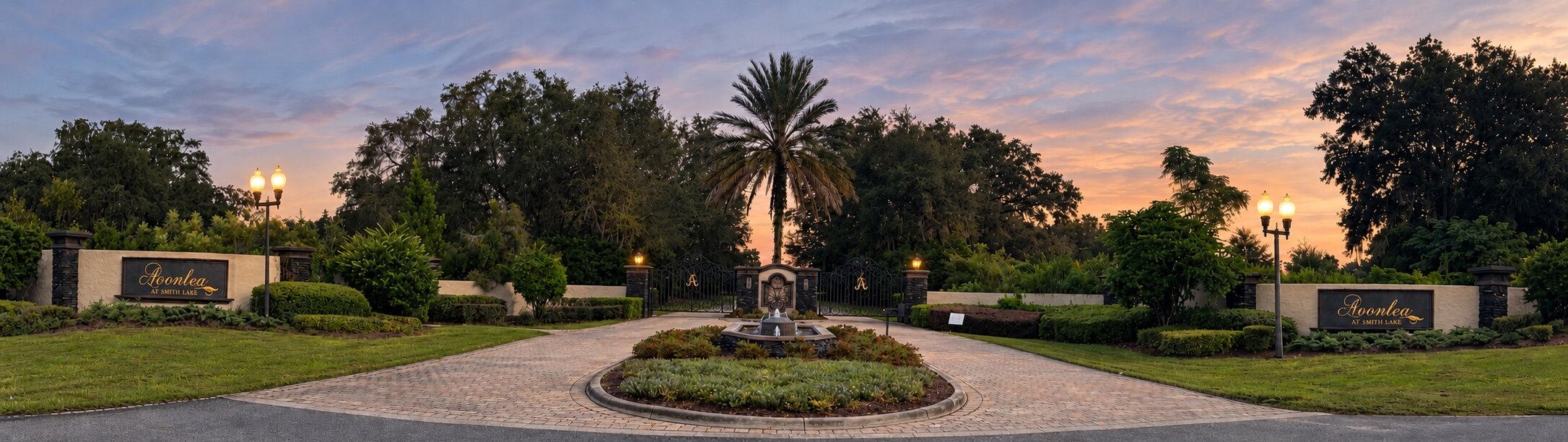 The Avonlea front gate at dusk, with the fountain and entrance signs on either side